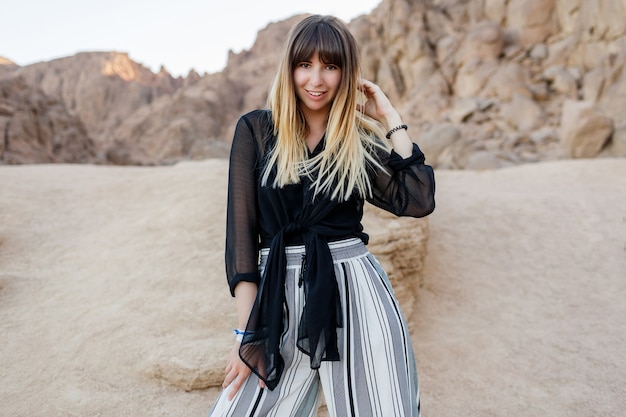 Elegante mujer morena posando en las dunas de arena del desierto egipcio.