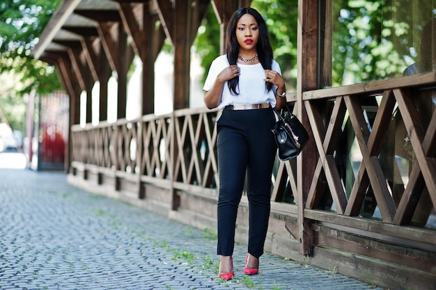 Elegante mujer de negocios afroamericana con bolso en las calles de la ciudad