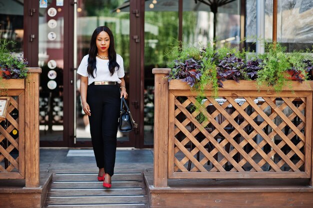 Elegante mujer de negocios afroamericana con bolso en las calles de la ciudad