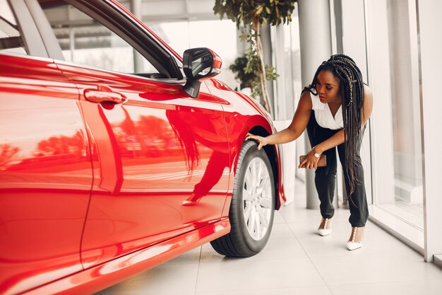 Elegante mujer negra en un salón de autos.