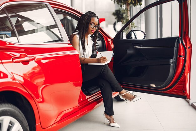 Elegante mujer negra en un salón de autos.