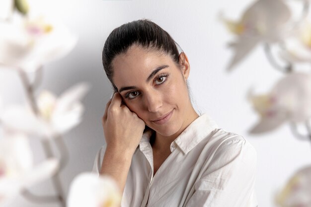 Elegante mujer posando con orquídeas desenfocadas