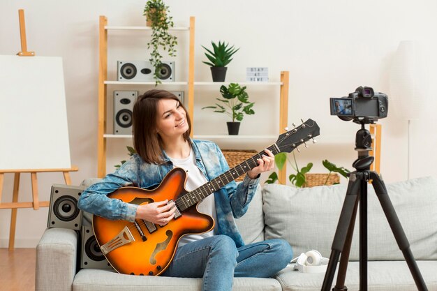 Elegante mujer recodificando mientras toca la guitarra