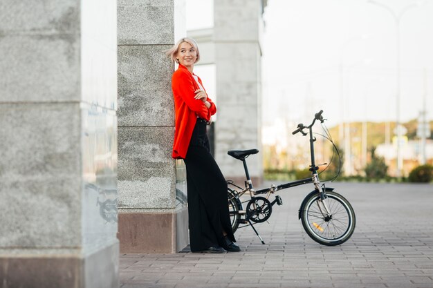 Elegante mujer rubia posando con su bicicleta