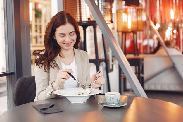 Elegante mujer sentada a la mesa con té y pasta