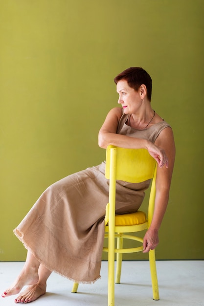 Elegante mujer sentada en una silla amarilla
