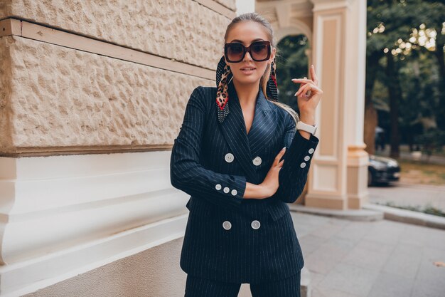 Elegante mujer sexy vestida con elegante traje de esmoquin caminando en la ciudad en verano primavera