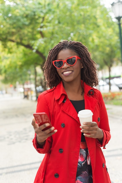 Elegante mujer con teléfono inteligente riendo en el parque