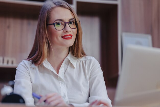 Elegante mujer trabaja en un escritorio portátil en una oficina moderna