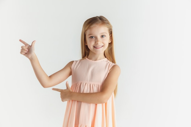 Elegante niña sonriente posando en vestido aislado en blanco studio