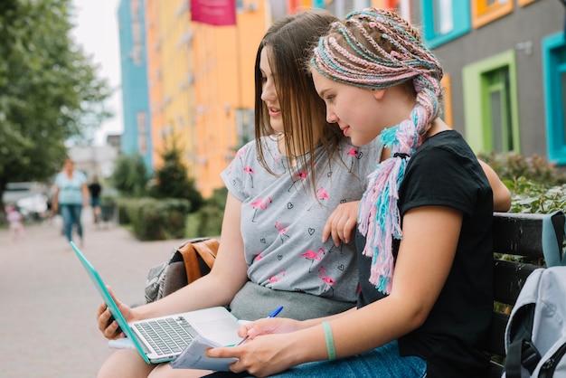 Elegante niñas estudiando con ordenador portátil en la calle