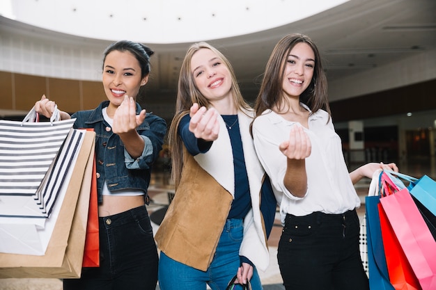 Elegante niñas gesticulando en la cámara con bolsas