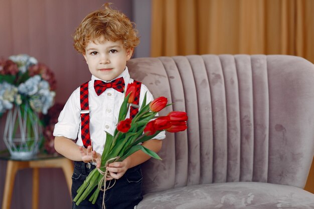 Elegante niño lindo con ramo de tulipán