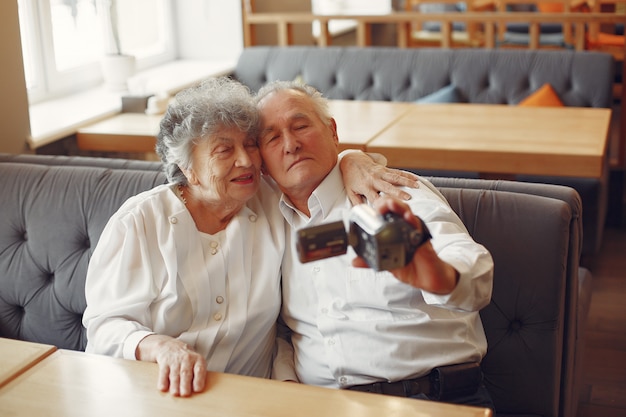 Elegante pareja de ancianos en un café con una cámara