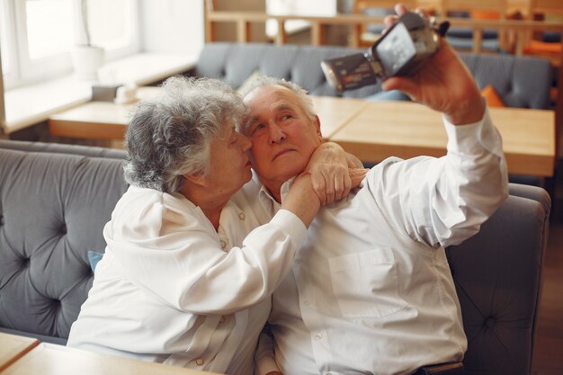 Elegante pareja de ancianos en un café con una cámara