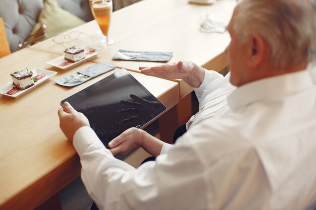 Elegante pareja de ancianos en un café con una tableta