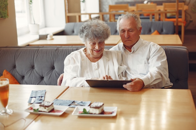 Elegante pareja de ancianos en un café con una tableta