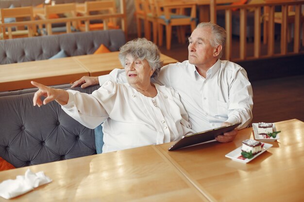 Elegante pareja de ancianos en un café con una tableta