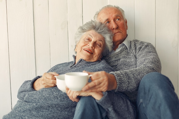 Elegante pareja de ancianos sentados en casa en un piso