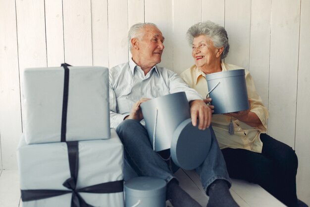 Elegante pareja de ancianos sentados en casa con regalos de navidad