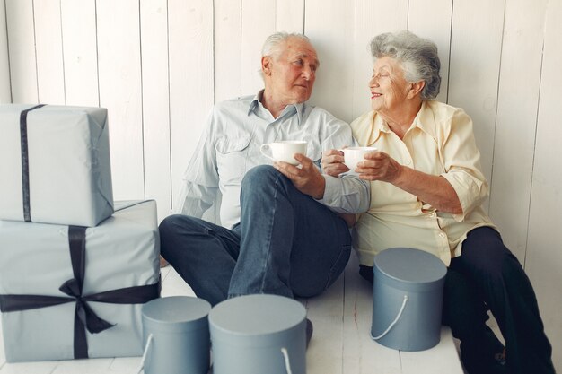 Elegante pareja de ancianos sentados en casa con regalos de navidad