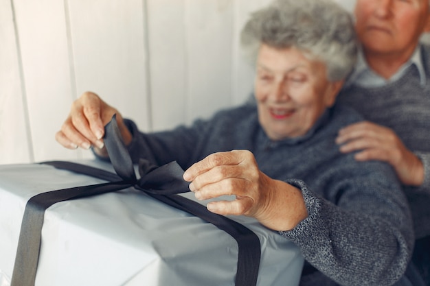 Elegante pareja de ancianos sentados en casa con regalos de navidad