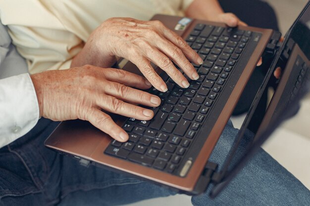 Elegante pareja de ancianos sentados en casa y usando una computadora portátil