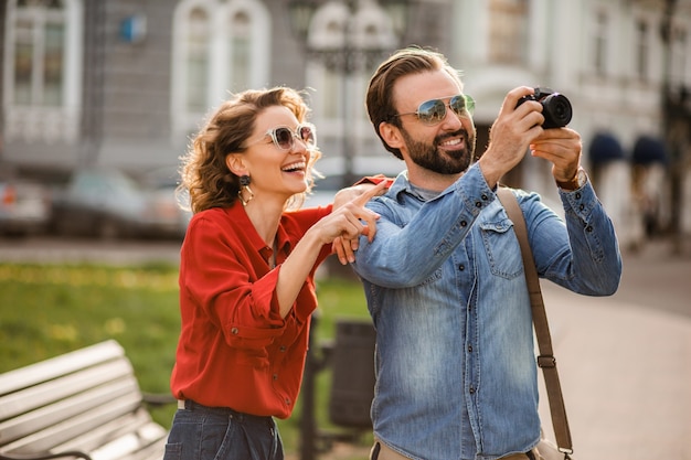 Elegante pareja de enamorados caminando abrazándose en la calle en un viaje romántico y tomando fotos