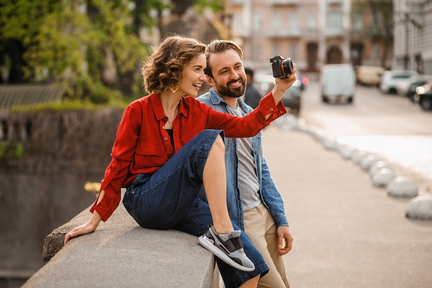 Elegante pareja de enamorados sentados en la calle en viaje romántico, tomando fotos