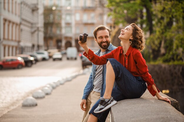 Elegante pareja de enamorados sentados en la calle en viaje romántico, tomando fotos