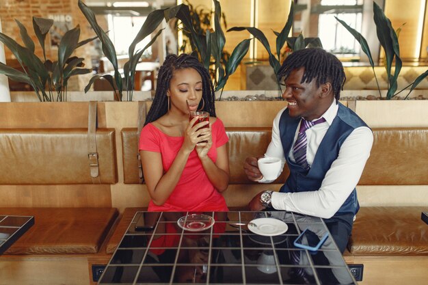 Elegante pareja negra sentada en un café y tomando un café