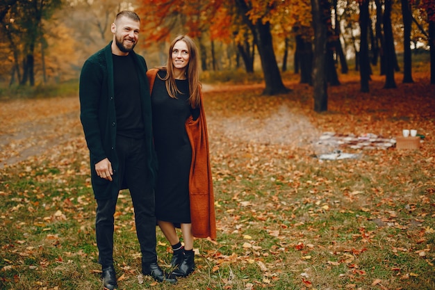 Elegante pareja pasa tiempo en un parque de otoño