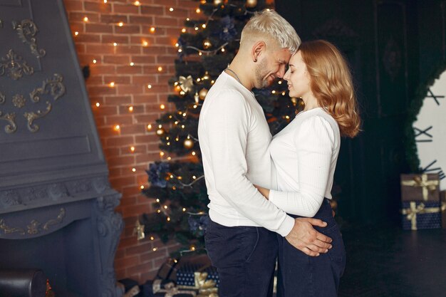 Elegante pareja de pie en casa cerca del árbol de Navidad