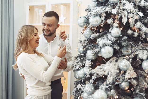 Elegante pareja de pie en casa cerca del árbol de Navidad