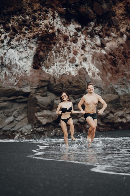 Elegante pareja en una playa cerca de rocas