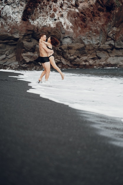 Elegante pareja en una playa cerca de rocas