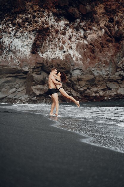 Elegante pareja en una playa cerca de rocas