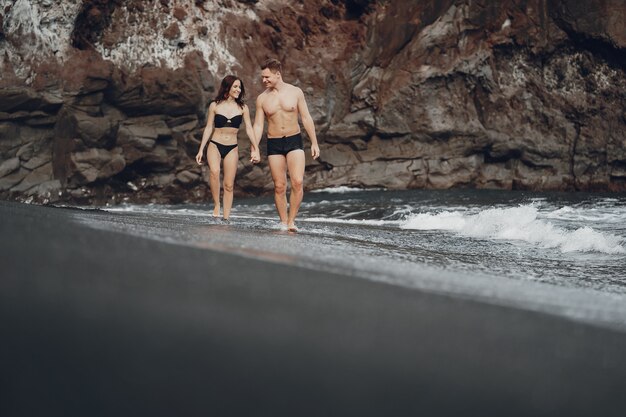 Elegante pareja en una playa cerca de rocas