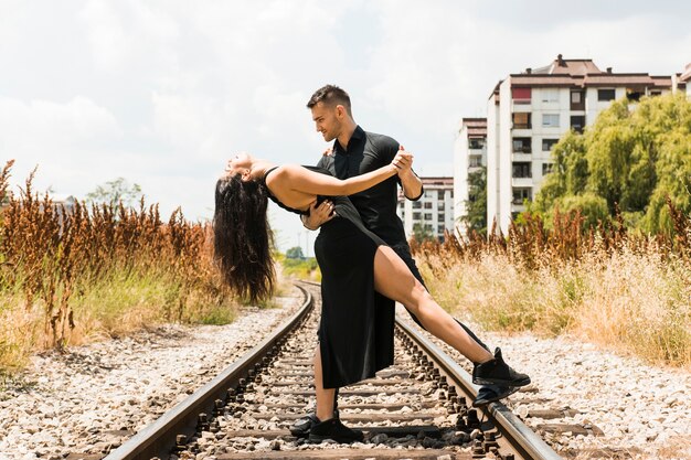 Elegante pareja romántica tangoing en la vía del tren