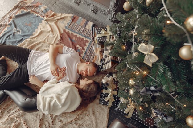 Elegante pareja sentada en casa cerca del árbol de navidad