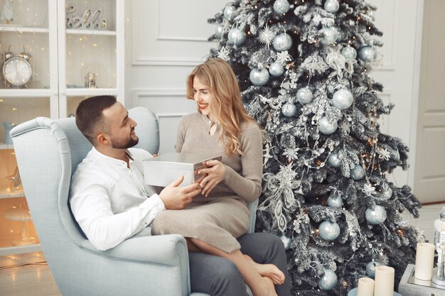 Elegante pareja sentada en casa cerca del árbol de navidad