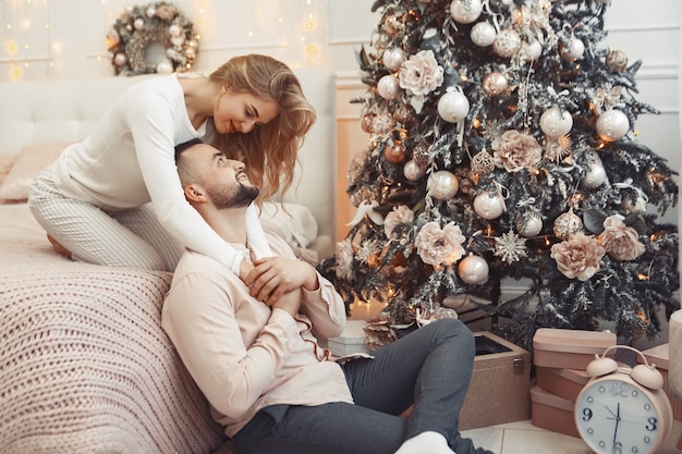 Elegante pareja sentada en casa cerca del árbol de navidad