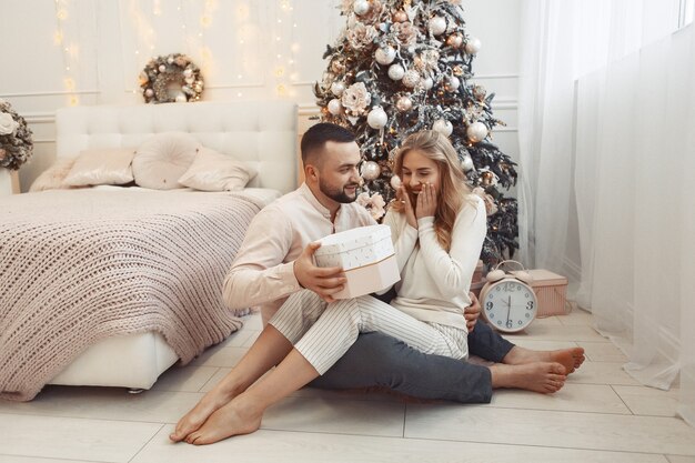 Elegante pareja sentada en casa cerca del árbol de navidad