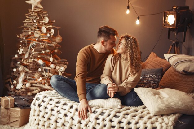 Elegante pareja sentada en casa cerca del árbol de navidad