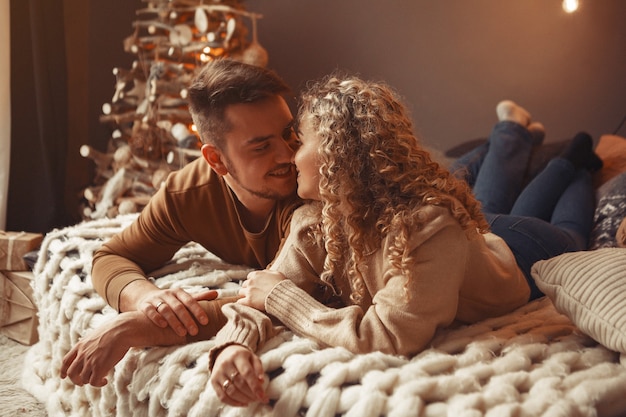 Elegante pareja sentada en casa cerca del árbol de navidad