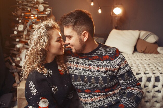 Elegante pareja sentada en casa cerca del árbol de navidad