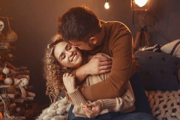 Elegante pareja sentada en casa cerca del árbol de navidad