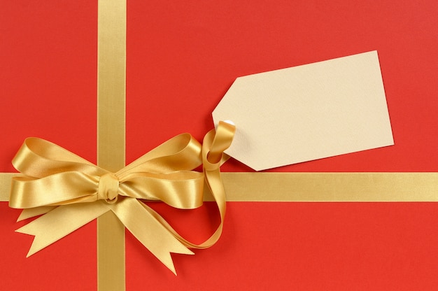 Elegante regalo rojo con un lazo dorado y etiqueta 