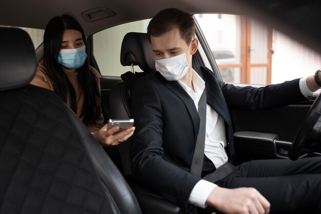 Elegante taxista y cliente en un coche con máscaras médicas