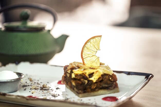 Elegante tetera verde con té y postre dulce. Tarta de manzana caramelizada con limón y helado frío